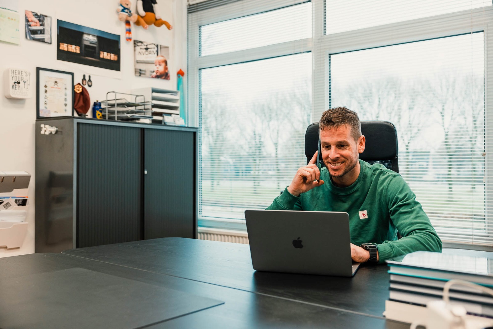 Jeroen Meijer aan bureau met telefoon en laptop.